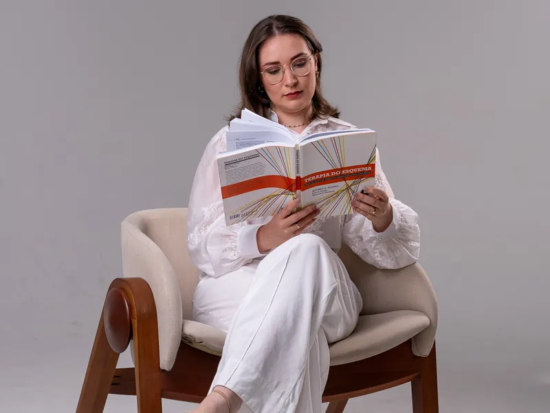 Psicóloga Eduarda Tartari lendo o livro Terapia do Esquema, representando supervisão clínica